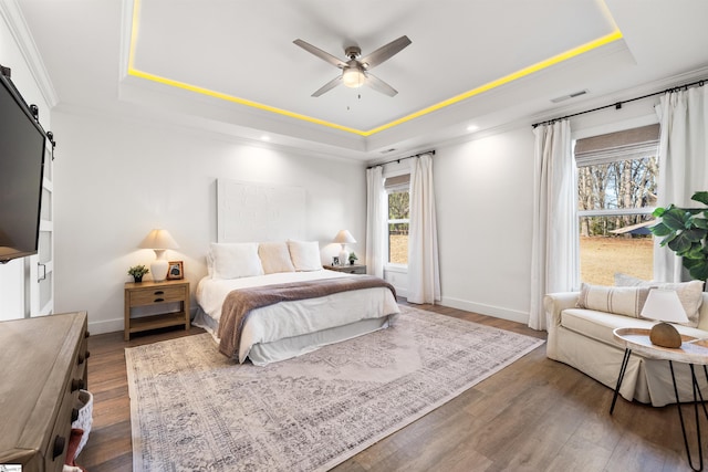 bedroom featuring a raised ceiling, a barn door, and ceiling fan