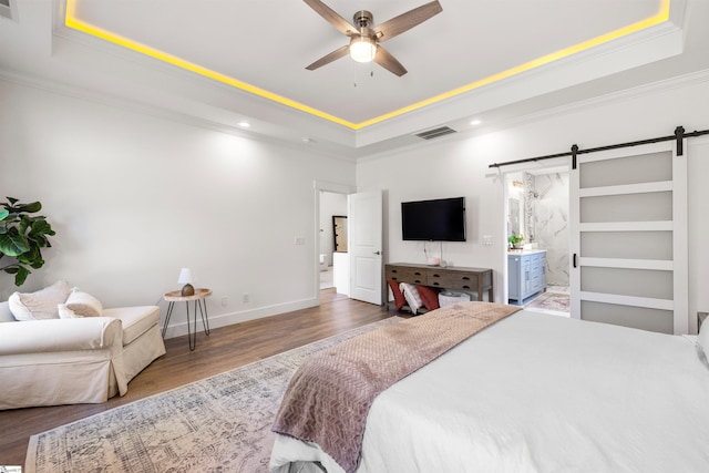 bedroom with a tray ceiling, ceiling fan, crown molding, a barn door, and dark hardwood / wood-style floors