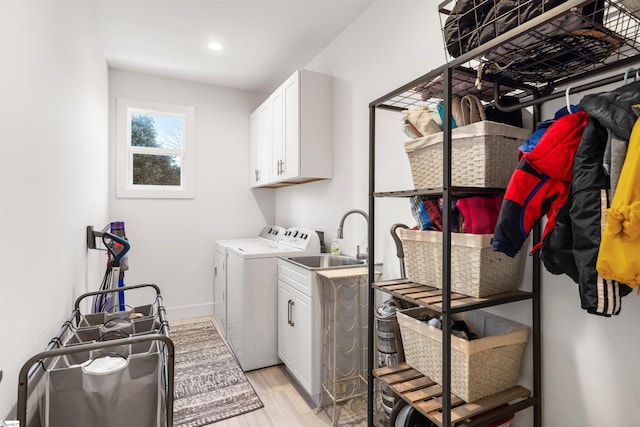 washroom with washer and dryer, cabinets, sink, and light hardwood / wood-style flooring