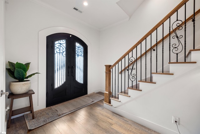 foyer with french doors, light hardwood / wood-style flooring, and crown molding