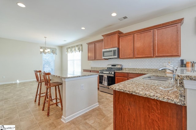 kitchen featuring stainless steel appliances, sink, an inviting chandelier, a center island, and hanging light fixtures