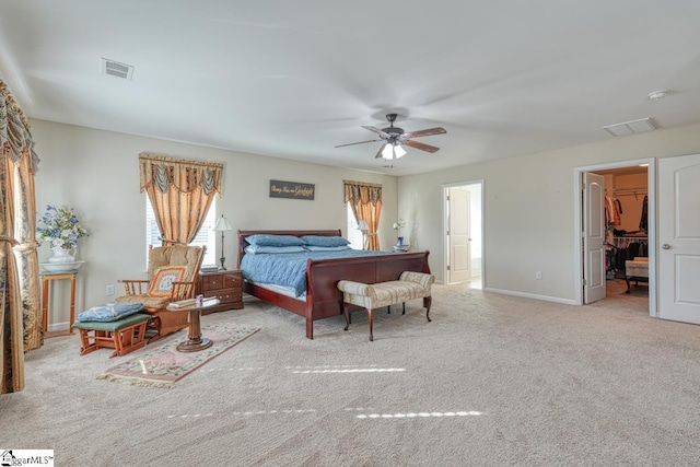 carpeted bedroom featuring a walk in closet, a closet, and ceiling fan