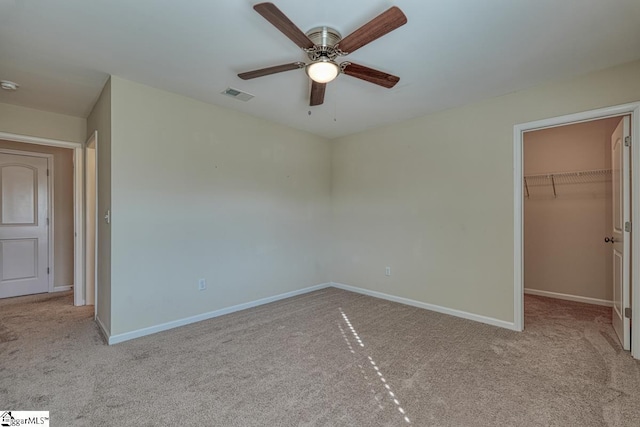 unfurnished bedroom with ceiling fan, light colored carpet, a spacious closet, and a closet