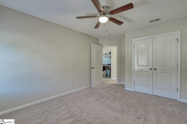 unfurnished bedroom featuring ceiling fan, a closet, and light colored carpet