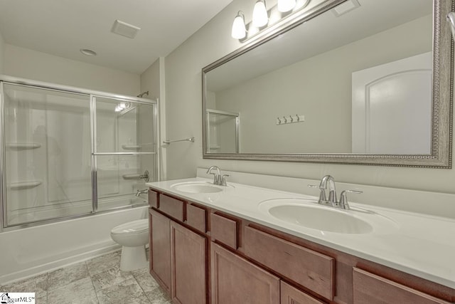 full bathroom with combined bath / shower with glass door, vanity, and toilet