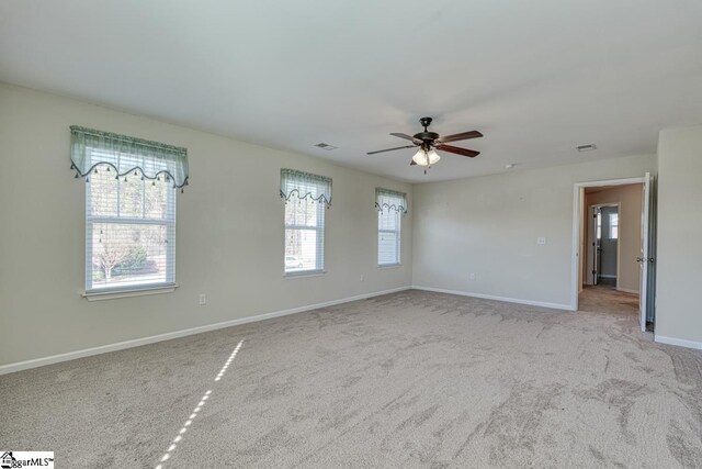 carpeted empty room with ceiling fan and plenty of natural light