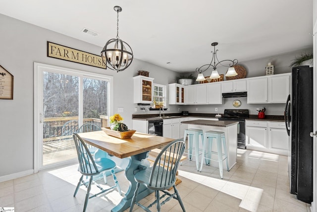 kitchen featuring a center island, white cabinets, black appliances, and decorative light fixtures