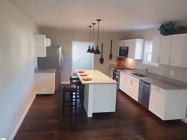 kitchen with pendant lighting, a center island, white cabinetry, stainless steel appliances, and sink