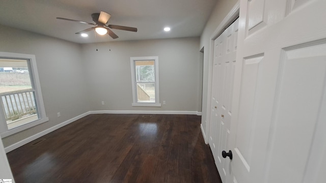 unfurnished bedroom with ceiling fan, multiple windows, and dark hardwood / wood-style floors