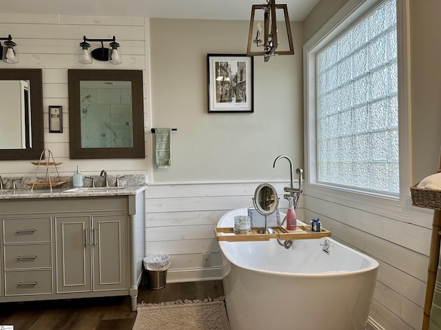 bathroom with wood walls, a washtub, vanity, and wood-type flooring