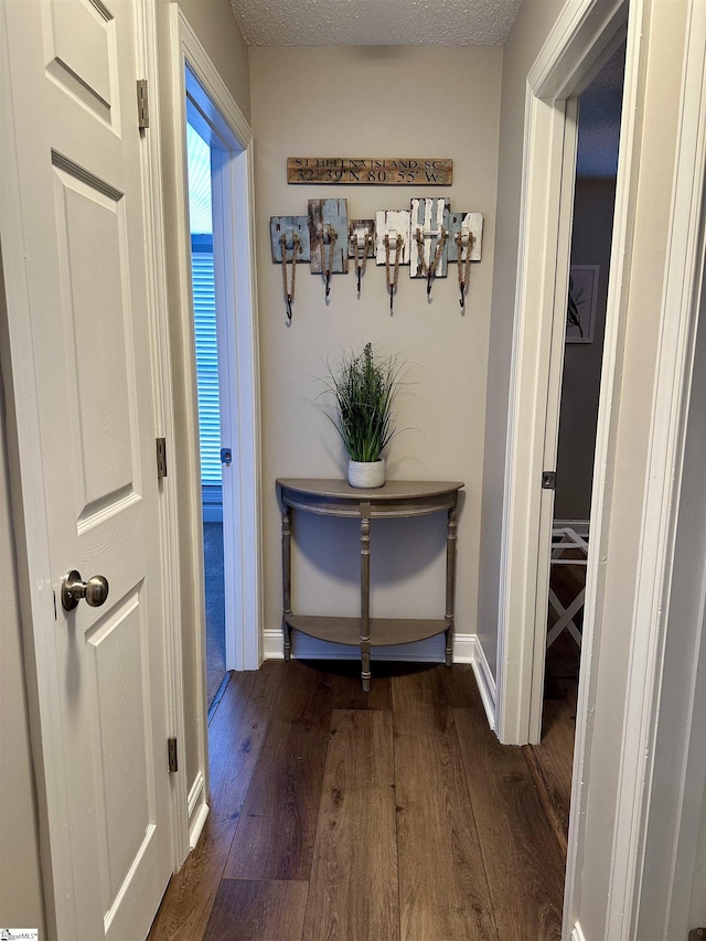 corridor with a textured ceiling and dark hardwood / wood-style floors