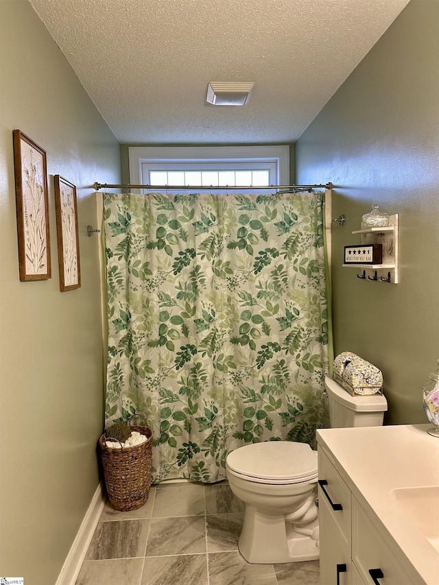 bathroom featuring vanity, a textured ceiling, and toilet