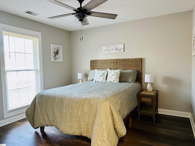 bedroom featuring ceiling fan, dark hardwood / wood-style floors, a textured ceiling, and multiple windows