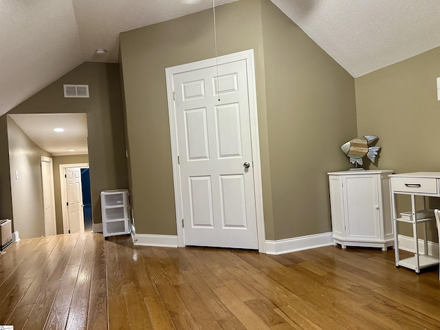 bonus room featuring wood-type flooring, lofted ceiling, and a textured ceiling