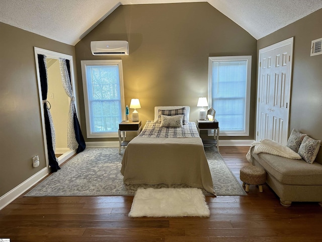 bedroom featuring a textured ceiling, dark hardwood / wood-style floors, and a wall unit AC