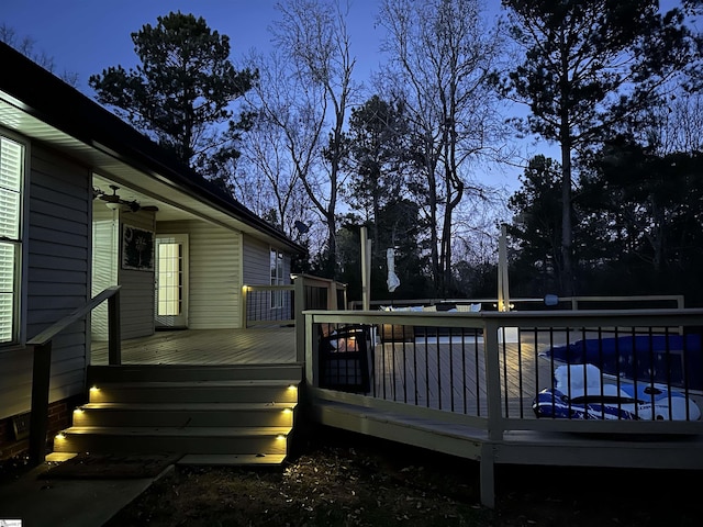 deck at dusk featuring a pool