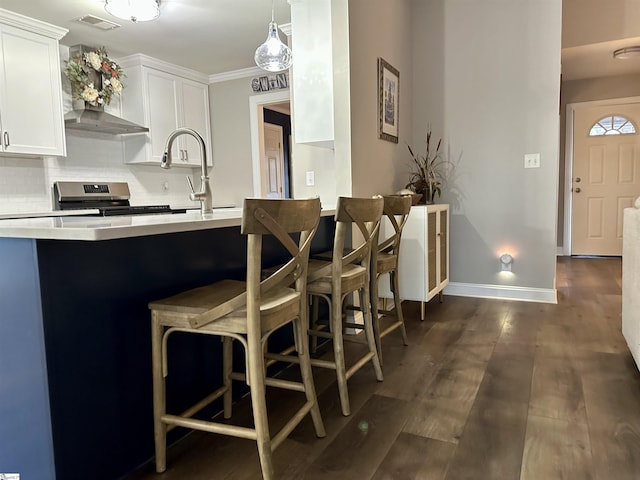 kitchen featuring dark wood-type flooring, a kitchen breakfast bar, tasteful backsplash, stainless steel range oven, and white cabinetry