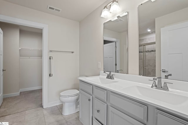 bathroom with tile patterned flooring, vanity, toilet, and an enclosed shower