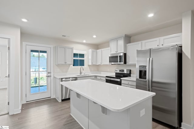 kitchen with a breakfast bar, sink, a kitchen island, white cabinetry, and stainless steel appliances