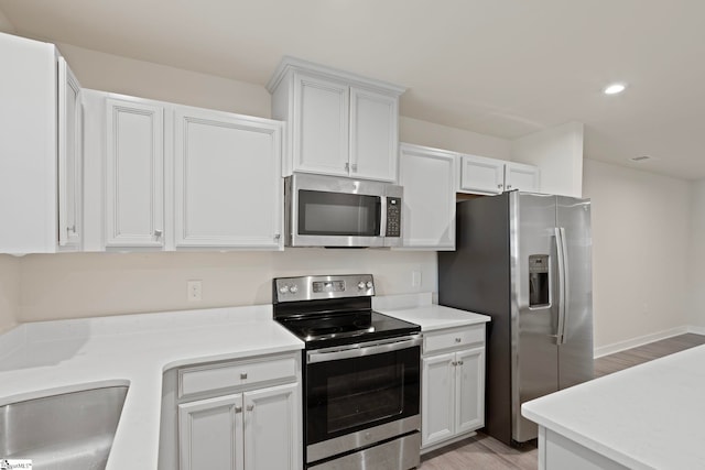 kitchen with light hardwood / wood-style floors, white cabinetry, sink, and appliances with stainless steel finishes