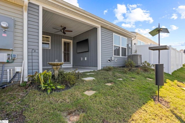 entrance to property featuring a lawn, ceiling fan, and central AC unit