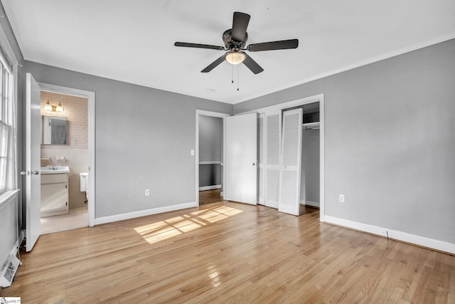 unfurnished bedroom featuring ceiling fan, light wood-type flooring, ornamental molding, and ensuite bath