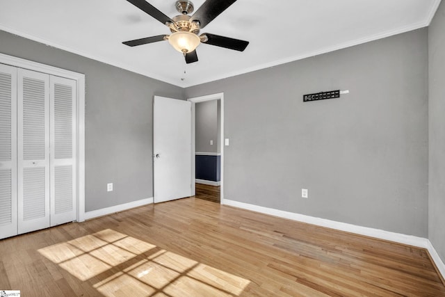 unfurnished bedroom with ceiling fan, a closet, wood-type flooring, and ornamental molding