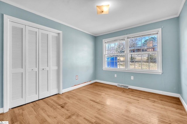 unfurnished bedroom with crown molding, a closet, and light hardwood / wood-style flooring