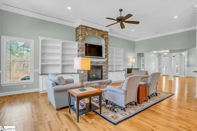 living room featuring ceiling fan, a fireplace, light hardwood / wood-style floors, and ornamental molding