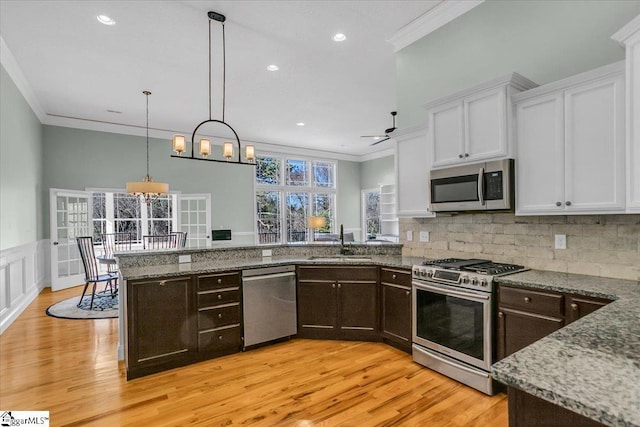 kitchen with stainless steel appliances, white cabinetry, ornamental molding, and sink