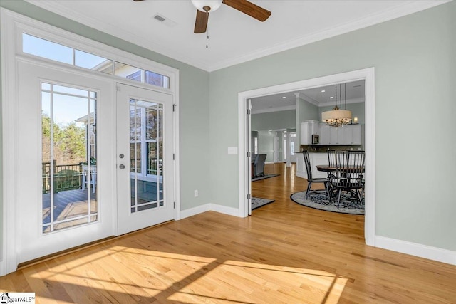 entryway featuring french doors, ceiling fan with notable chandelier, ornamental molding, and wood-type flooring