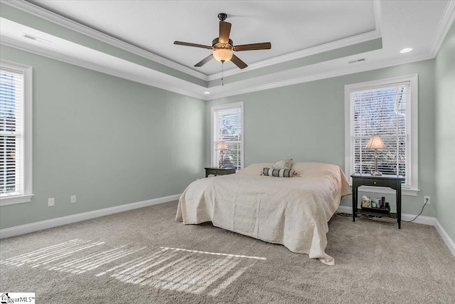 bedroom with a tray ceiling, multiple windows, ceiling fan, and crown molding