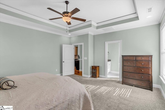 carpeted bedroom with ceiling fan, a raised ceiling, crown molding, and connected bathroom