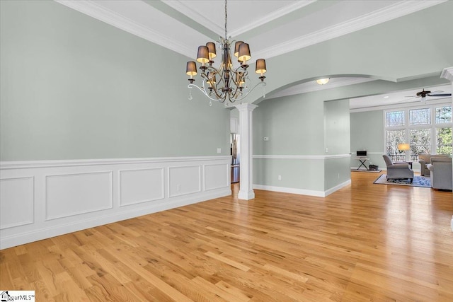 unfurnished room featuring ceiling fan with notable chandelier, light wood-type flooring, decorative columns, and crown molding