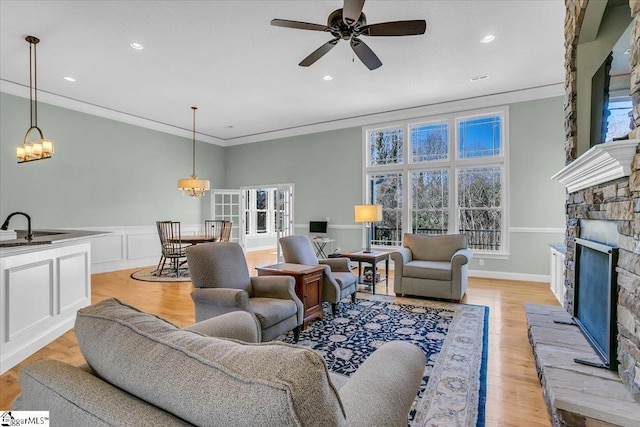 living room featuring a fireplace, light hardwood / wood-style floors, crown molding, and ceiling fan with notable chandelier