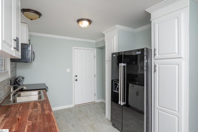 kitchen with white cabinetry, black fridge, butcher block counters, and sink