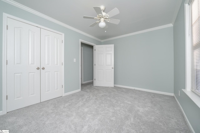 unfurnished bedroom with crown molding, ceiling fan, a closet, and light colored carpet