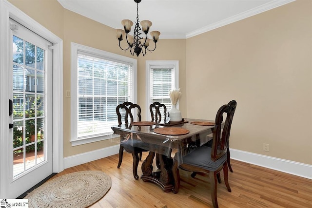 dining area with light wood-type flooring, ornamental molding, and a chandelier