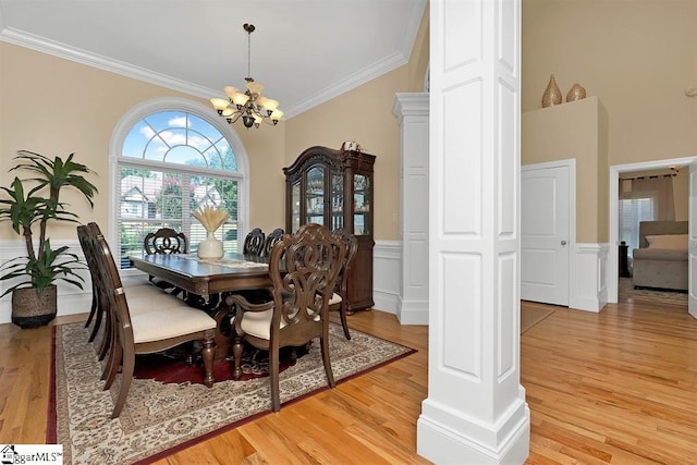 dining space featuring ornamental molding, light wood-type flooring, ornate columns, and a notable chandelier