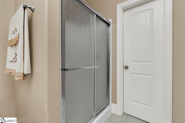 bathroom with tile patterned floors and a shower with door