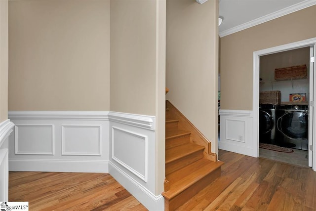 staircase featuring hardwood / wood-style flooring, independent washer and dryer, and crown molding