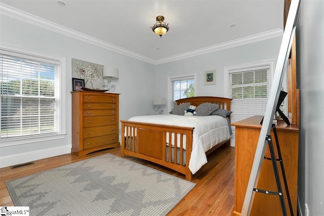 bedroom with light hardwood / wood-style flooring, multiple windows, and ornamental molding