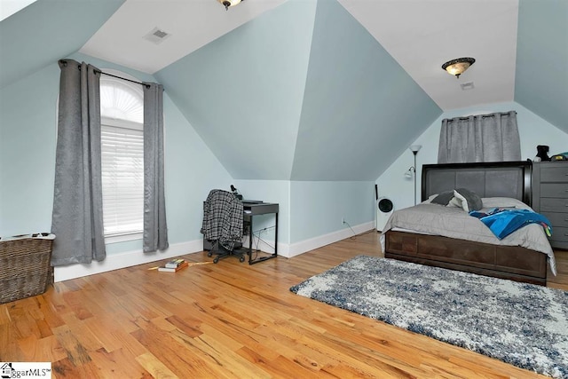 bedroom with hardwood / wood-style floors, vaulted ceiling, and multiple windows