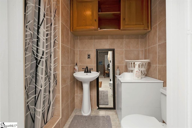 bathroom with tile patterned flooring, a shower with curtain, toilet, and tile walls