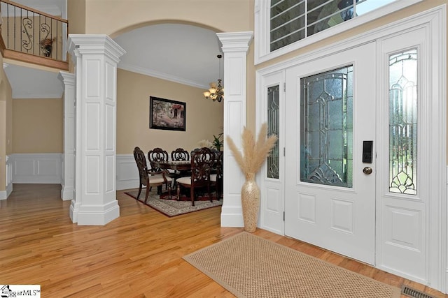 entrance foyer with a chandelier, hardwood / wood-style floors, ornate columns, and ornamental molding