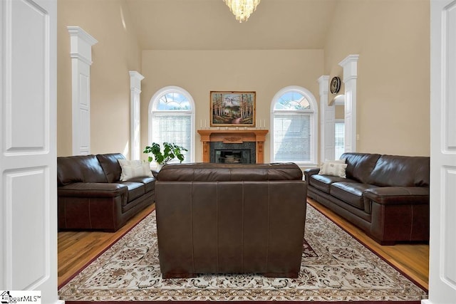 living room with hardwood / wood-style flooring, ornate columns, and lofted ceiling