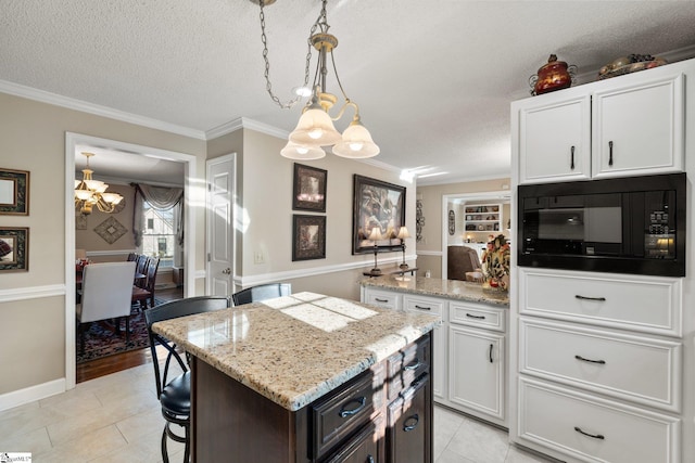 kitchen with a textured ceiling, white cabinetry, black microwave, and hanging light fixtures