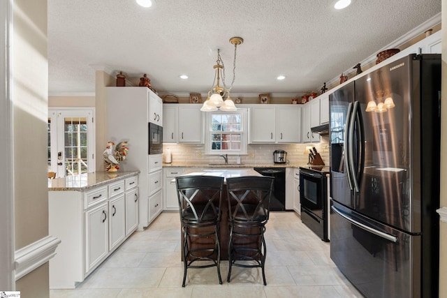 kitchen featuring black appliances, pendant lighting, white cabinetry, and sink