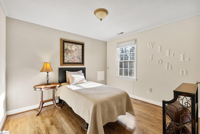 bedroom featuring hardwood / wood-style floors, a textured ceiling, and crown molding