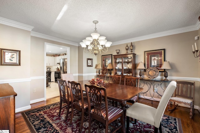 dining space with a notable chandelier, dark wood-type flooring, a textured ceiling, and ornamental molding